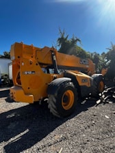 A sturdy JCB machine working on a busy construction site under a clear sky.