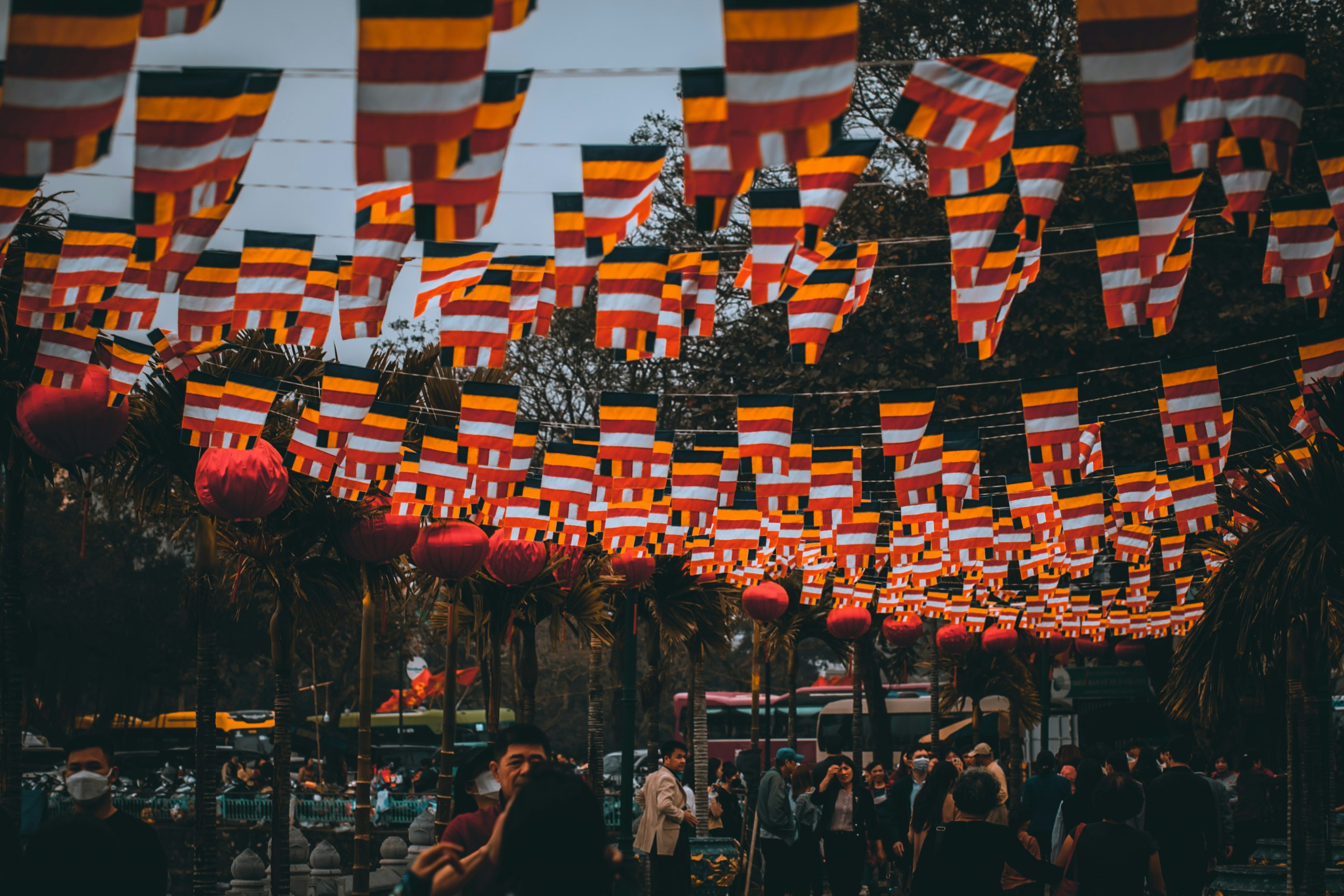 a crowd of people standing under flags hanging from a line