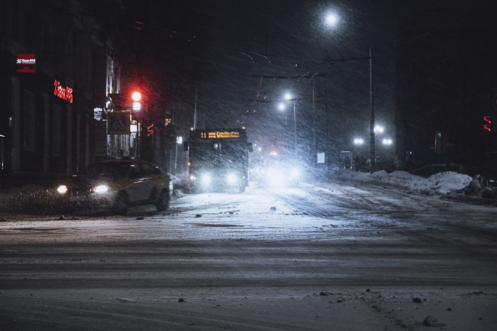 a car driving down a snow covered street at night