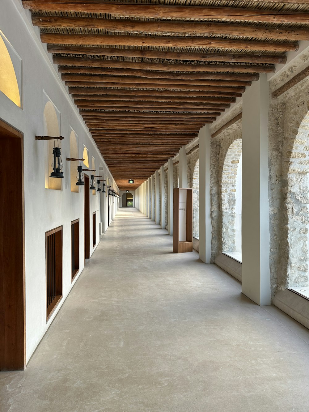 un lungo corridoio con finestre ad arco e un soffitto in legno