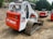 Multiple tracked skid steer loaders are parked on a dirt surface. The machinery, labeled with the brand name Bobcat and model T300, has a combination of white and bright red colors. The vehicles are surrounded by a natural setting, with trees in the background and construction materials nearby.
