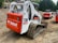 Multiple tracked skid steer loaders are parked on a dirt surface. The machinery, labeled with the brand name Bobcat and model T300, has a combination of white and bright red colors. The vehicles are surrounded by a natural setting, with trees in the background and construction materials nearby.