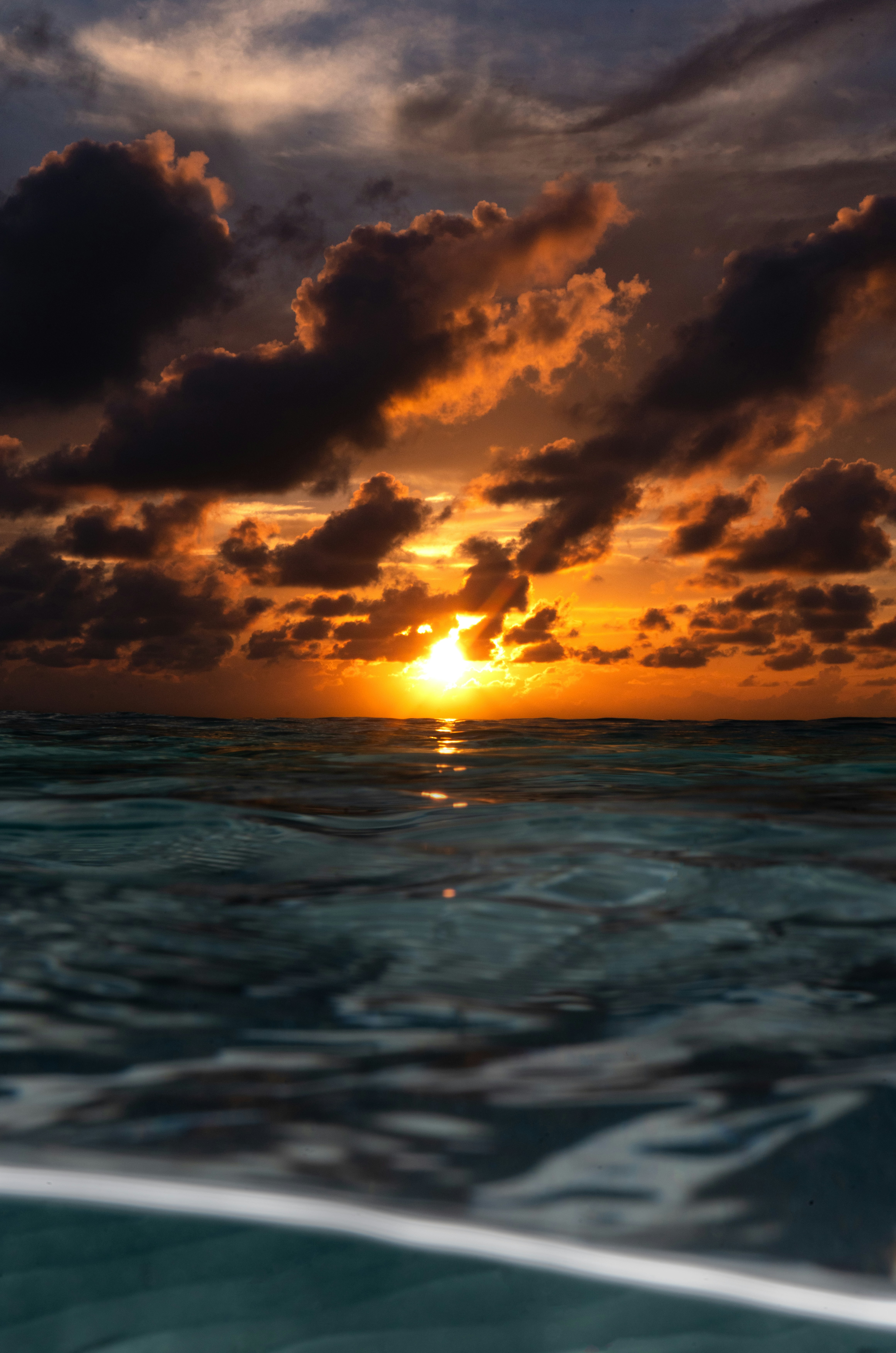 the sun is setting over the ocean as seen from a boat