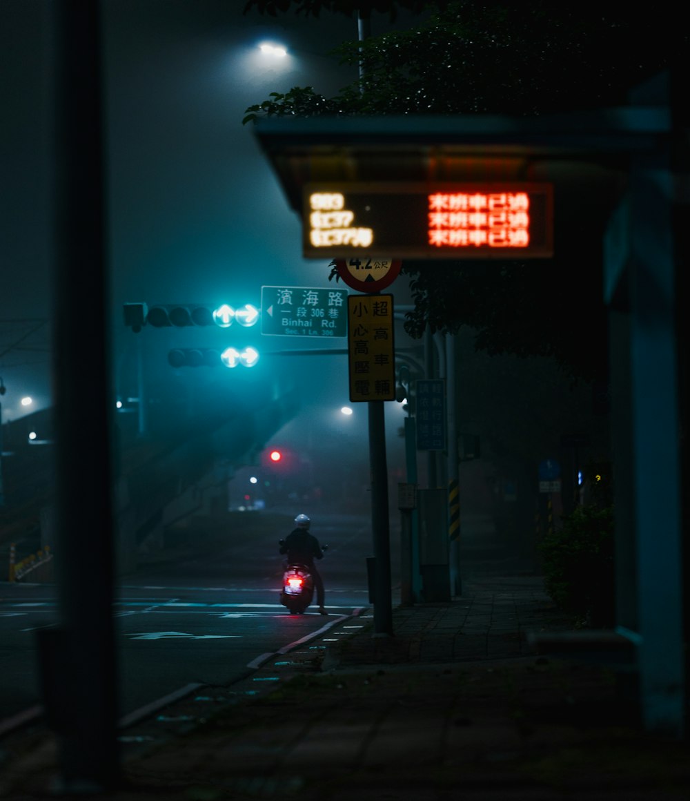 a person riding a motorcycle down a street at night