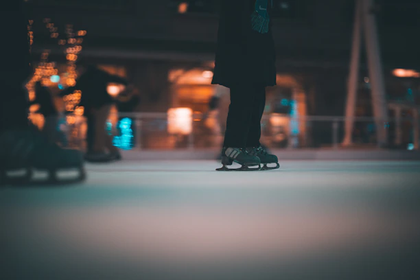 A close-up shot of skaters' blades gliding smoothly over shimmering ice under soft blue lights.