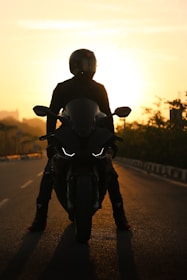 Viker Knight leaning against his bike at sunset, with a backdrop of winding roads.