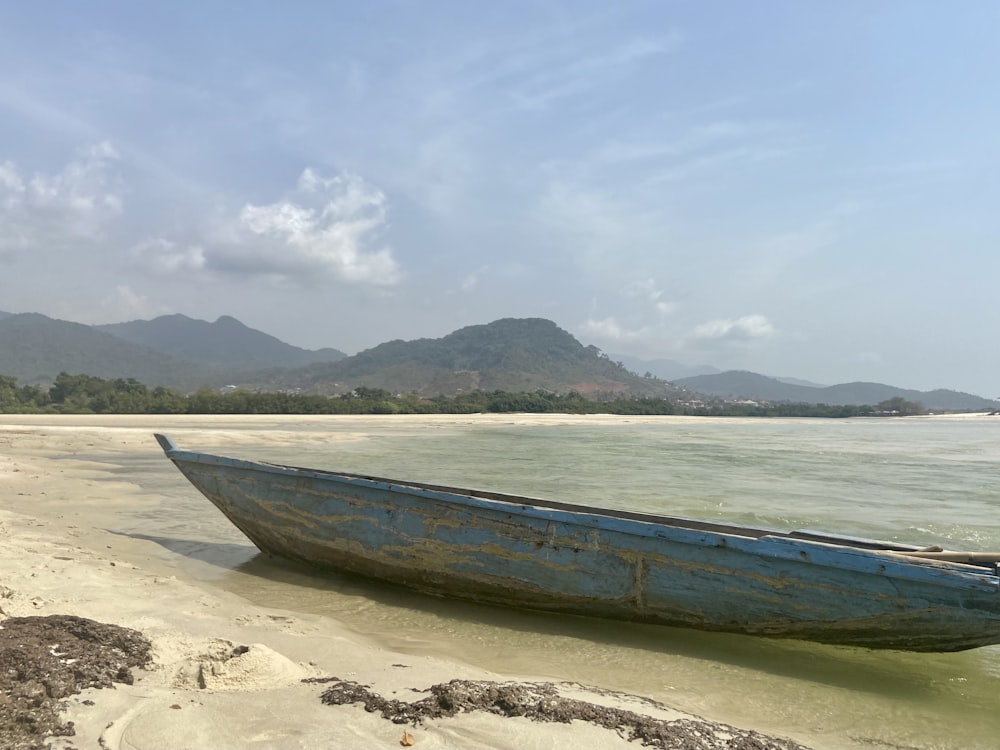 Un bateau bleu assis au sommet d’une plage de sable