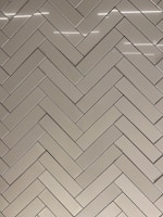 Modern ceramic floor tiles arranged in a herringbone pattern in a bright showroom.