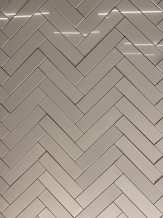 a bathroom with a white tiled wall and a toilet