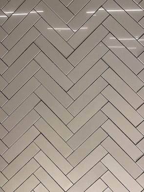 Modern ceramic floor tiles arranged in a herringbone pattern in a bright showroom.