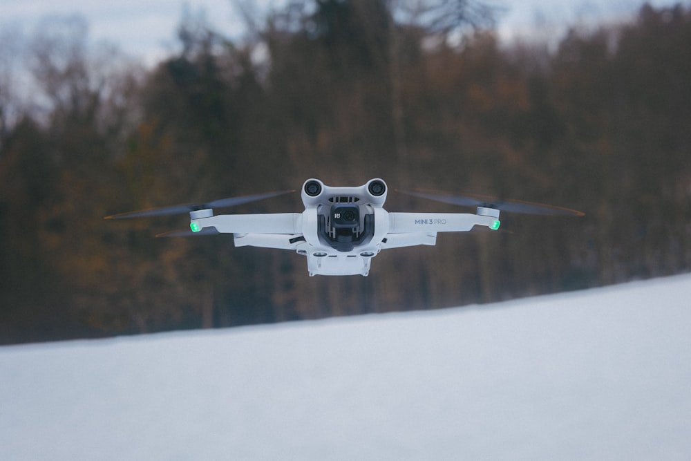 a small white plane flying over a snow covered field