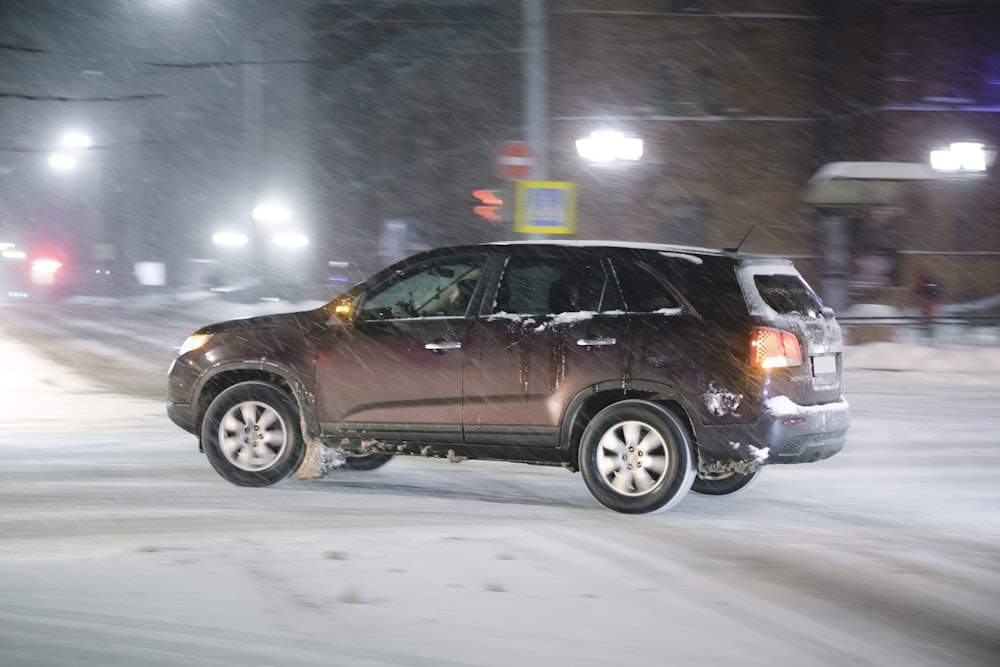 a car driving down a snowy street at night