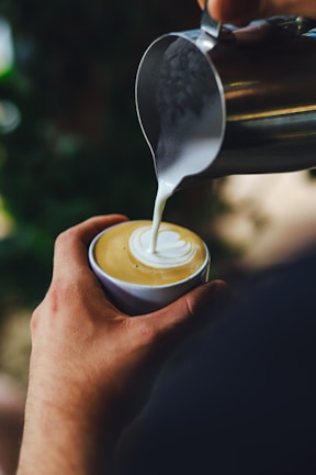 Barista pouring steamed milk to create a swan design on a cappuccino.
