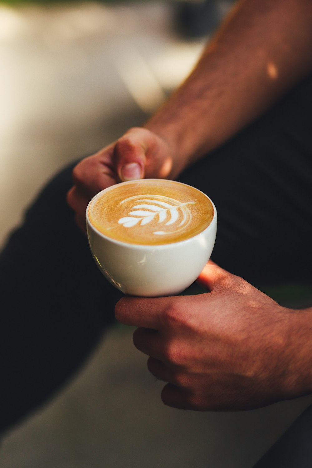 a person holding a cup of coffee in their hand