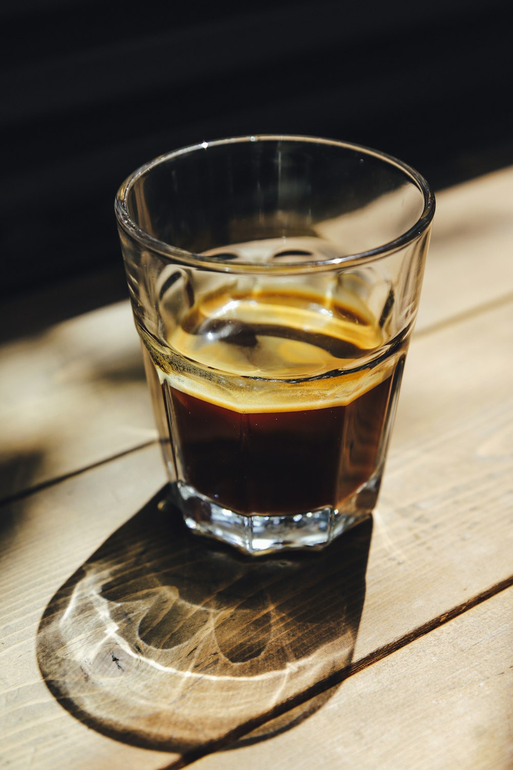 a glass of liquid sitting on top of a wooden table