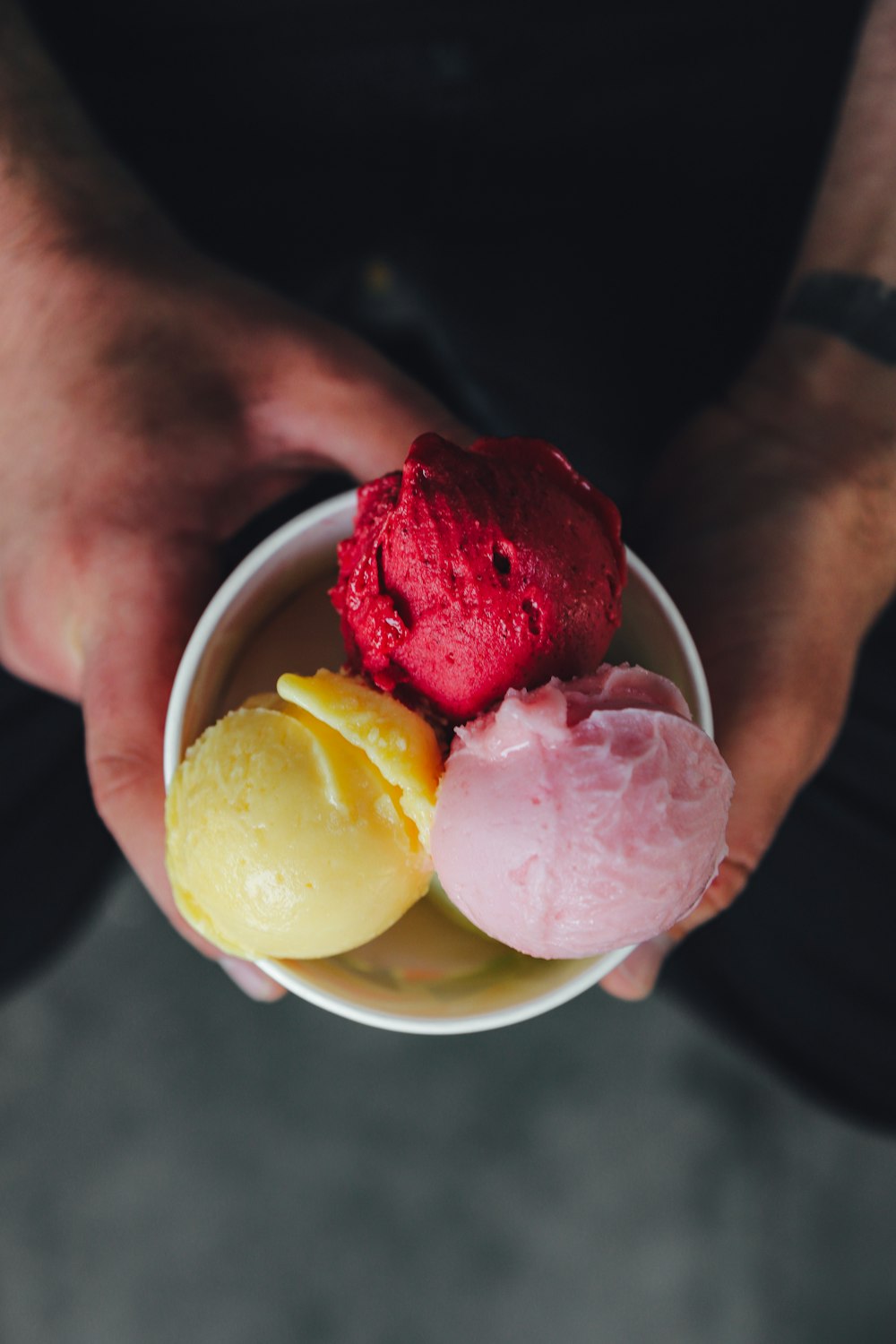 a person holding a bowl of ice cream and fruit