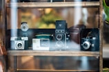 A collection of luxury cameras displayed on a glass shelf with soft lighting.