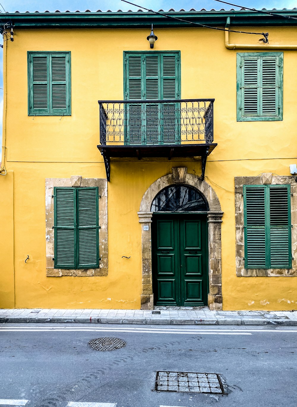 a yellow building with green shutters and a balcony