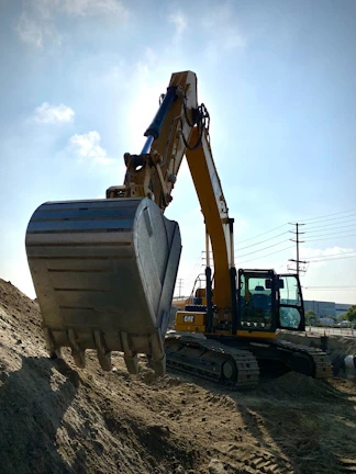 Close-up of moling machine cutting through South African soil under a bright blue sky.
