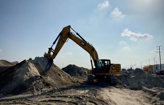 A rugged excavator at a construction site in Abu Dhabi under a clear blue sky.