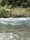Clear water flows gently over a rocky surface with a lush, green forest in the background.