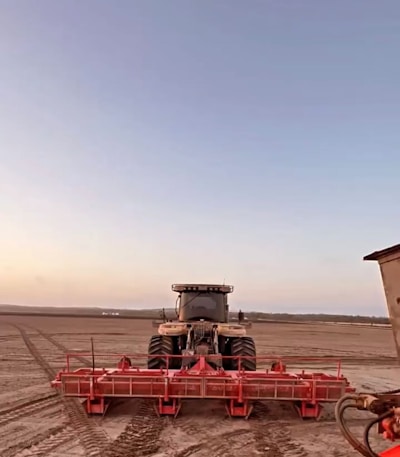 A sturdy tractor equipped with heavy-duty tires parked in a field at sunrise