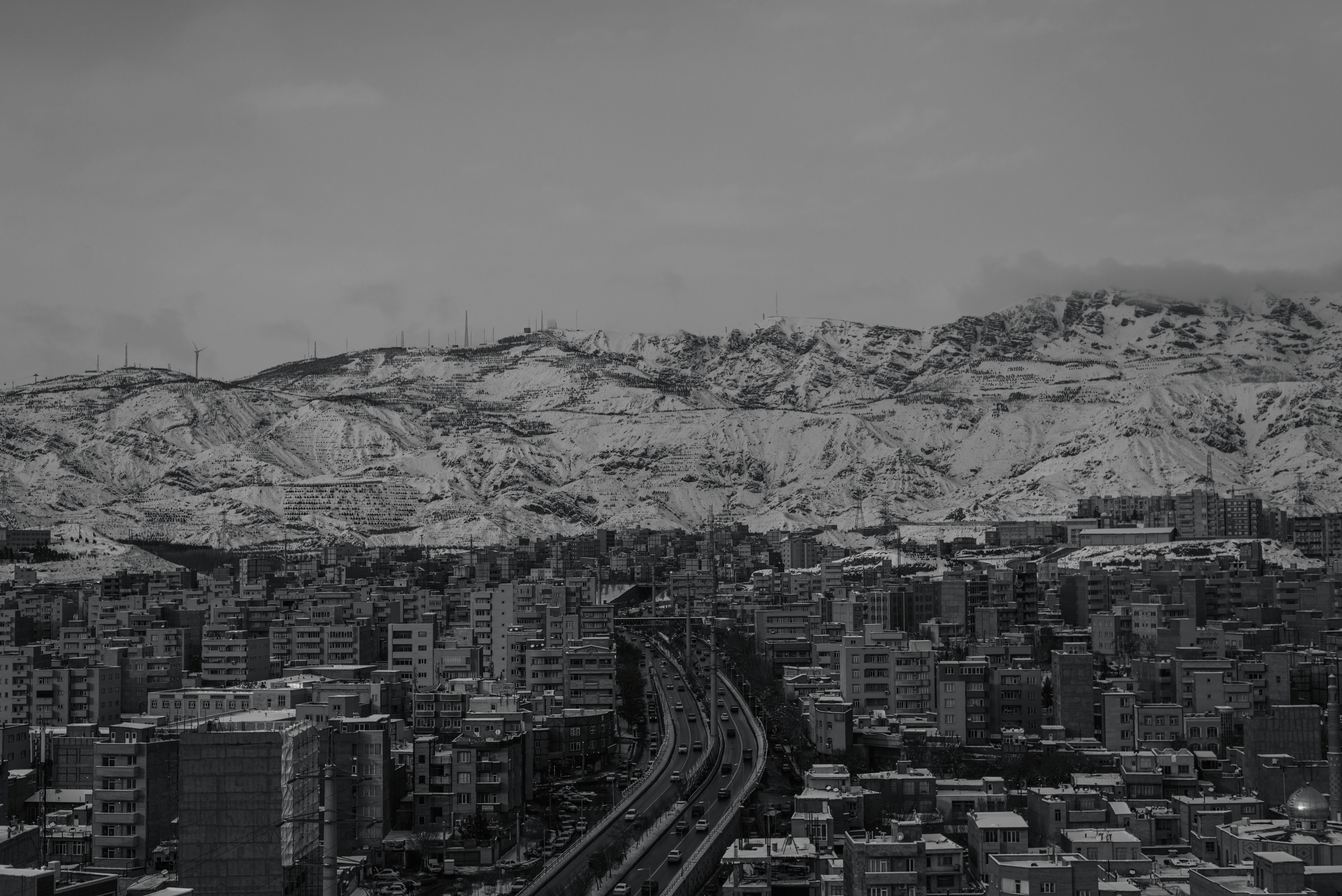 a black and white photo of a city with mountains in the background