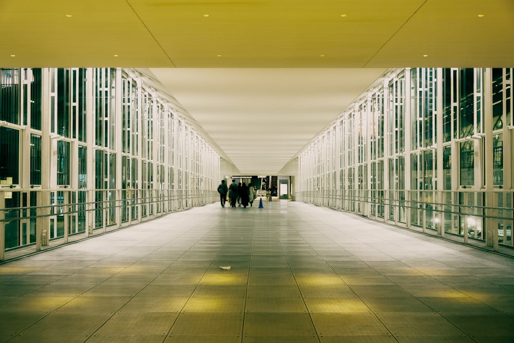 two people walking down a long hallway between two buildings