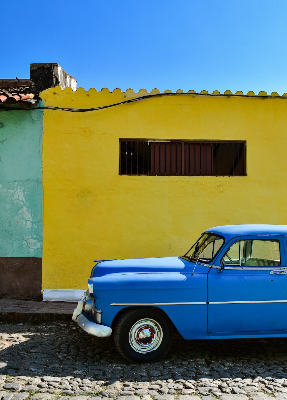 a blue car parked in front of a yellow building