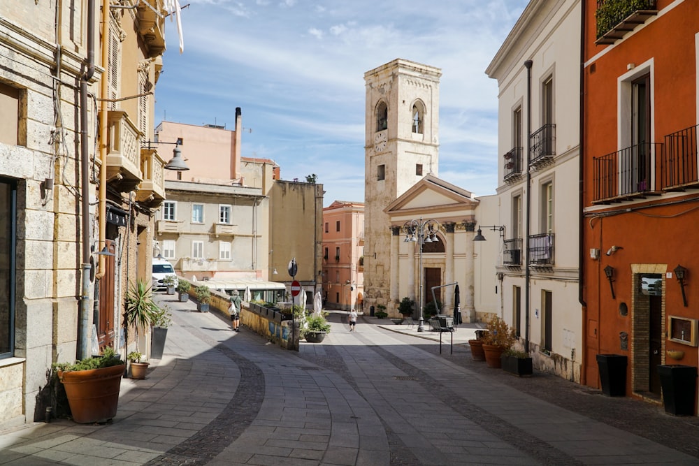 a narrow street with a clock tower in the background