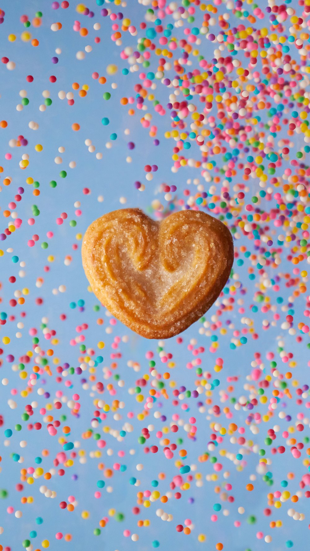 a heart shaped pastry sitting on top of a table covered in sprinkles