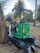 Photo of a compact mini-excavator carefully leveling a small garden area surrounded by dense greenery.
