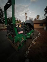 Heavy machinery compacting asphalt on a residential street surrounded by palm trees.