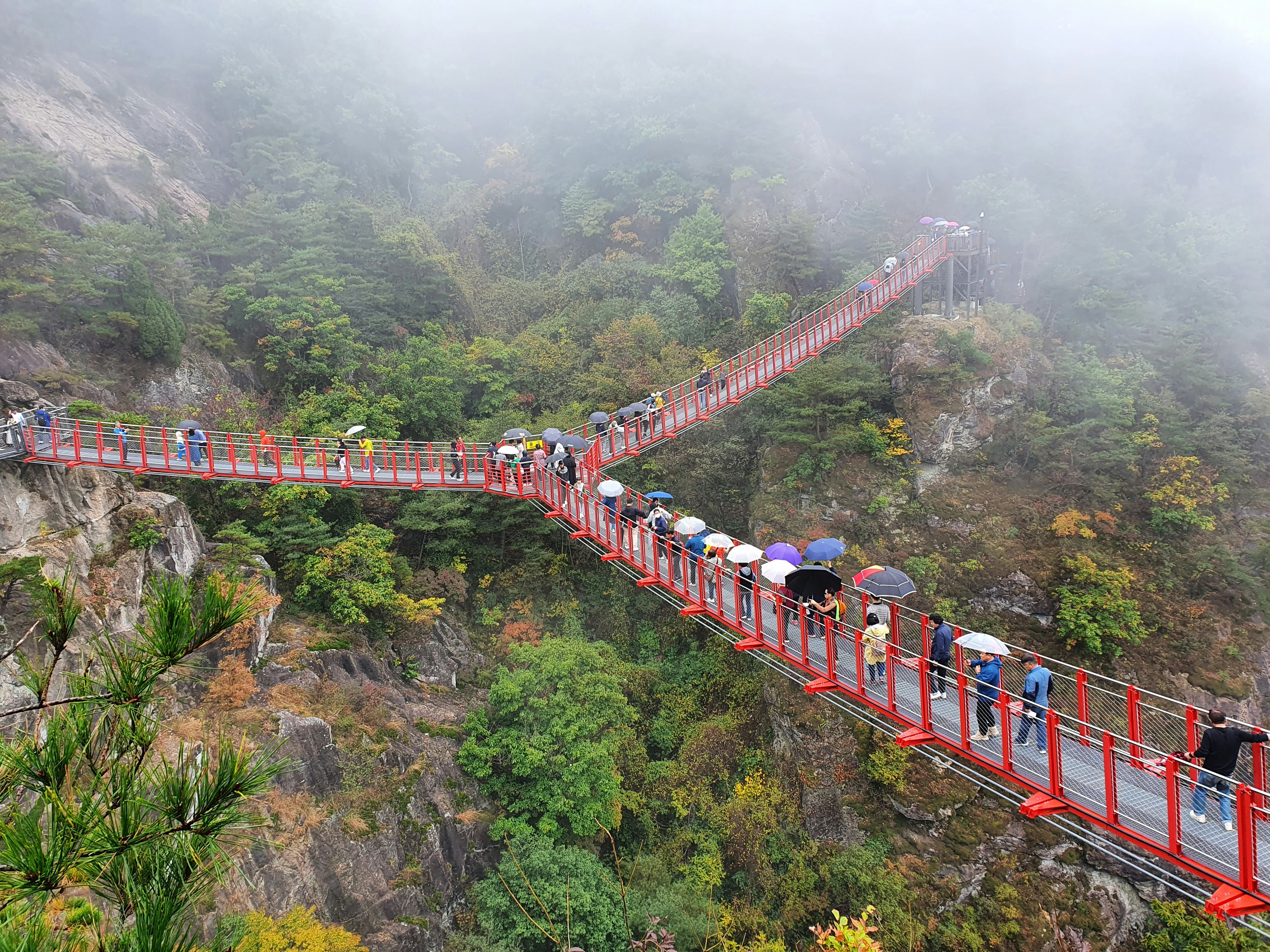 a group of people walking across a red bridge