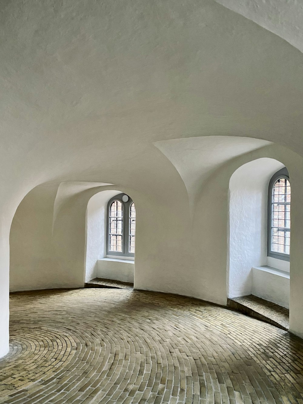 a circular room with arched windows and a brick floor
