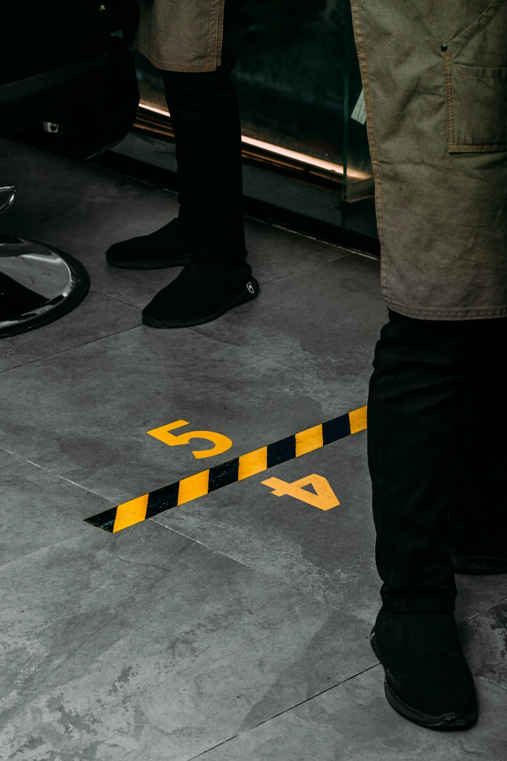 a pair of legs standing next to a yellow and black caution line