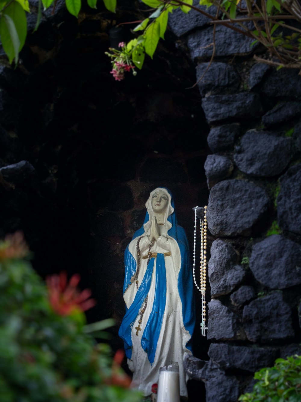 a statue of the virgin mary in a garden