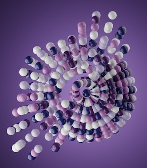 A complex, swirling formation of spheres arranged in a spiral pattern against a purple background. The spheres appear to be made of a glossy material and are colored in shades of white, purple, and blue. The structure gives an impression of depth and movement through its layered arrangement.