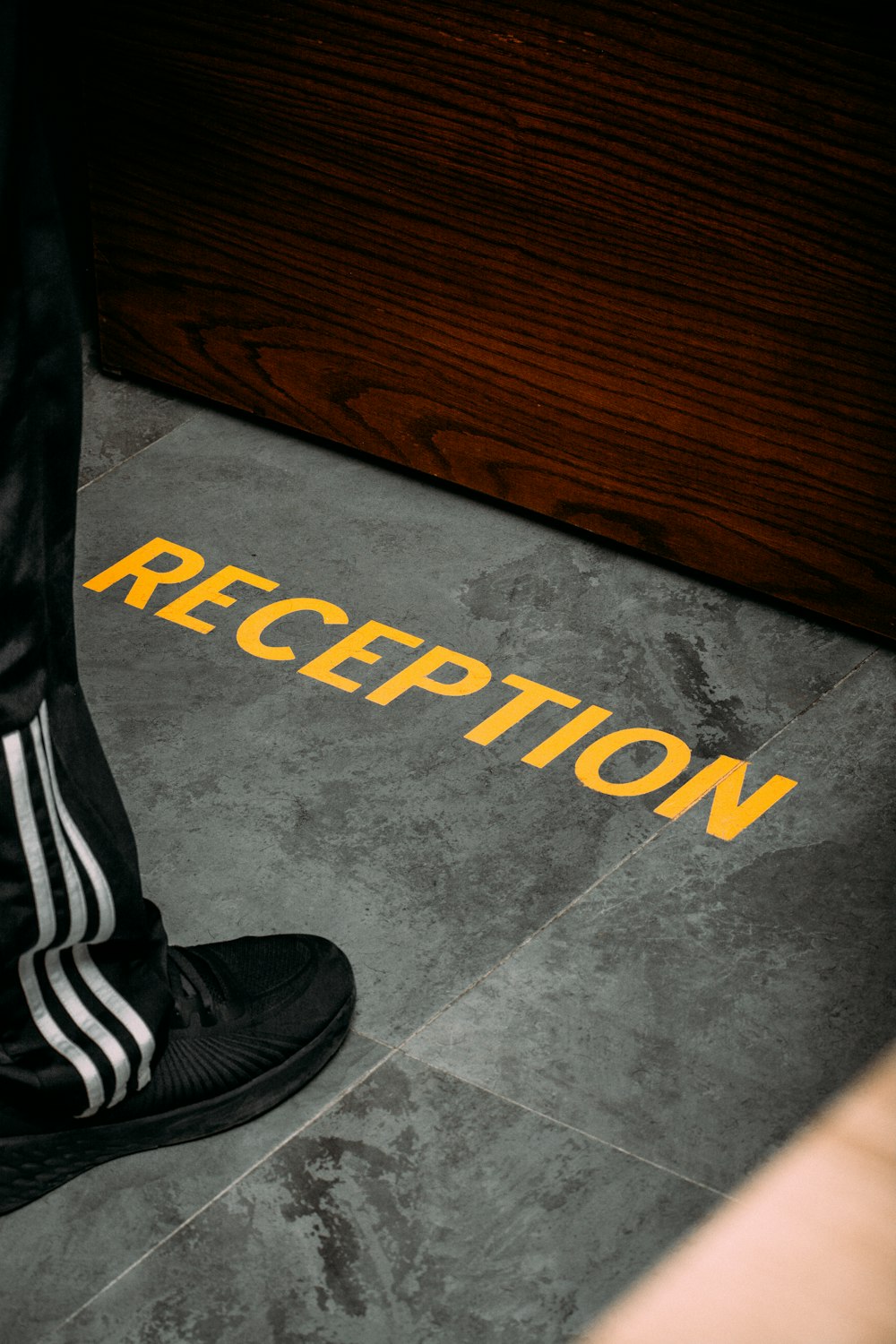 a person standing on a floor with a pair of black shoes