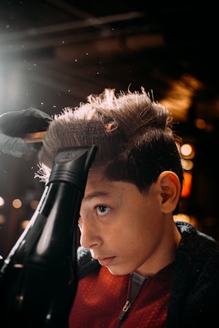 a boy with a hair dryer on his head