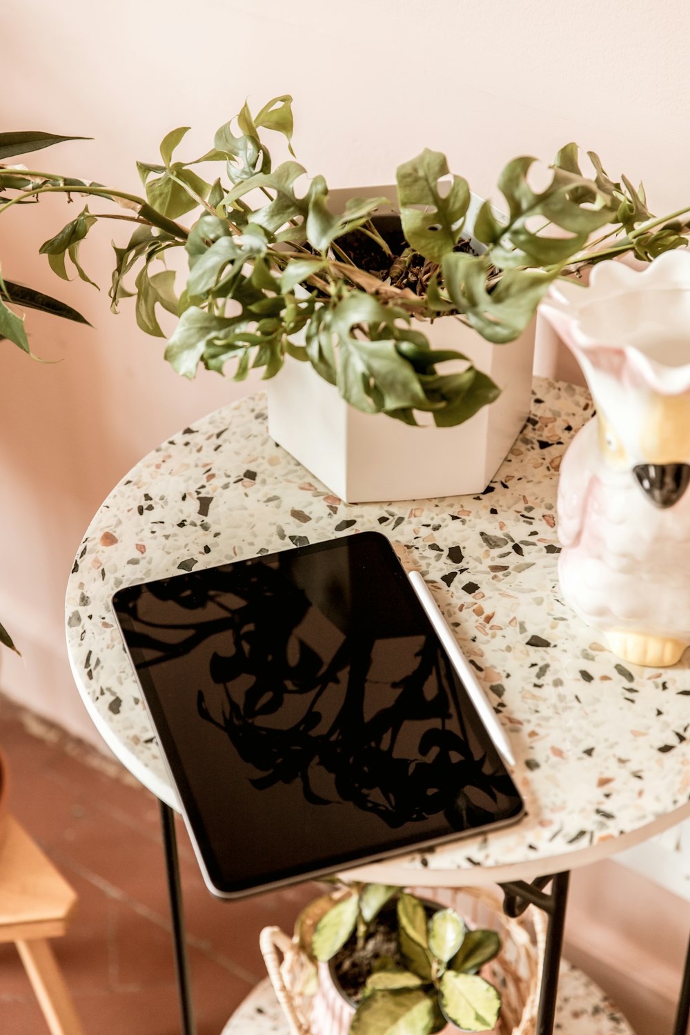 a tablet sitting on a table next to a potted plant
