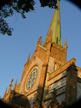 Dramatic dusk photo showcasing the full church facade with its stone walls and stained glass windows lit from within.