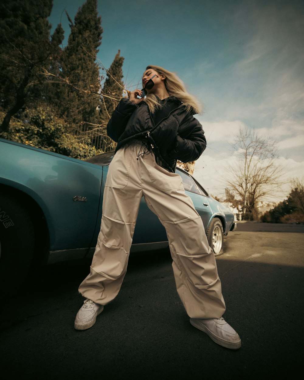 a woman standing next to a car talking on a cell phone