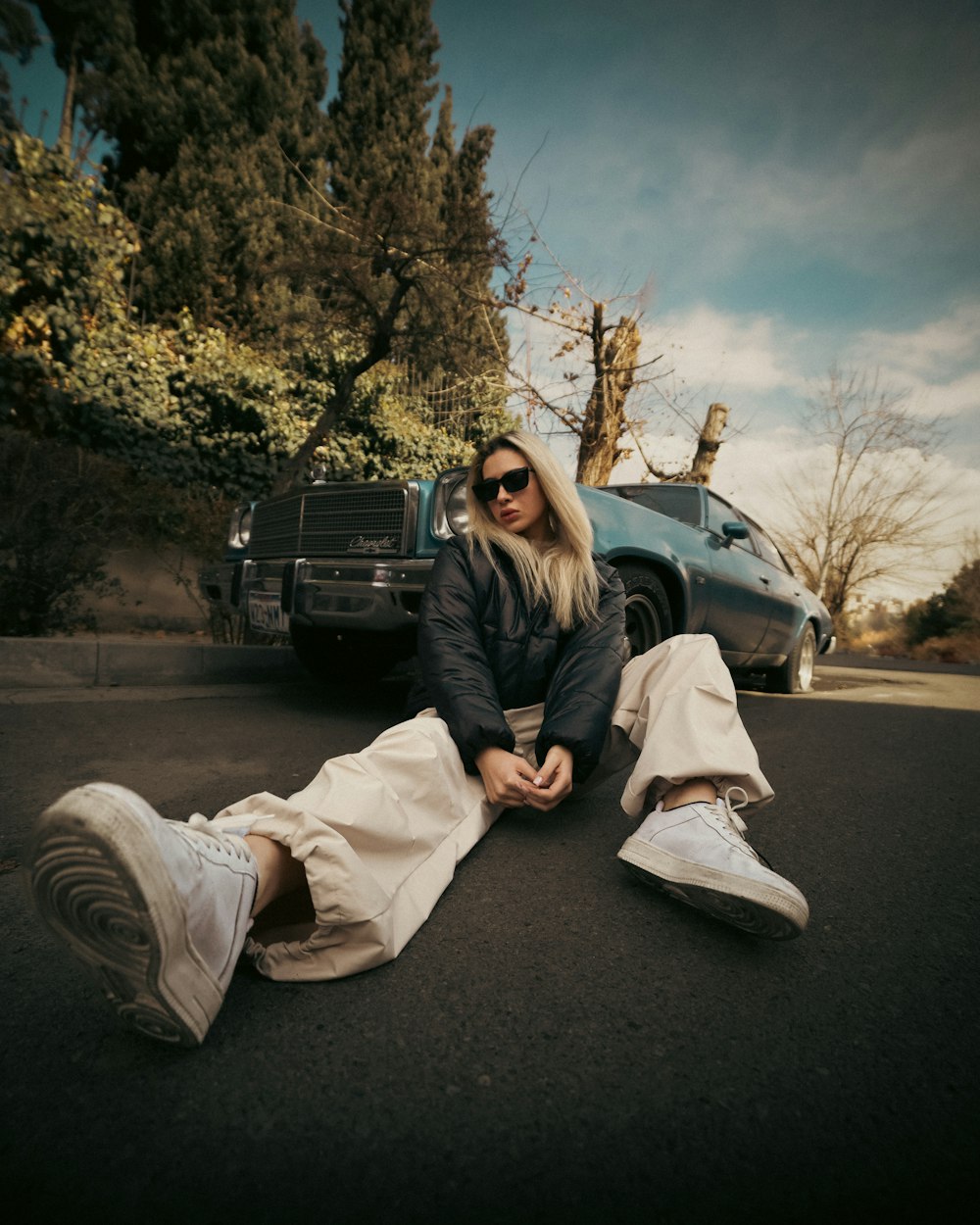 a woman sitting on the ground next to a car