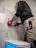 a man in a black shirt and red gloves working on a toilet