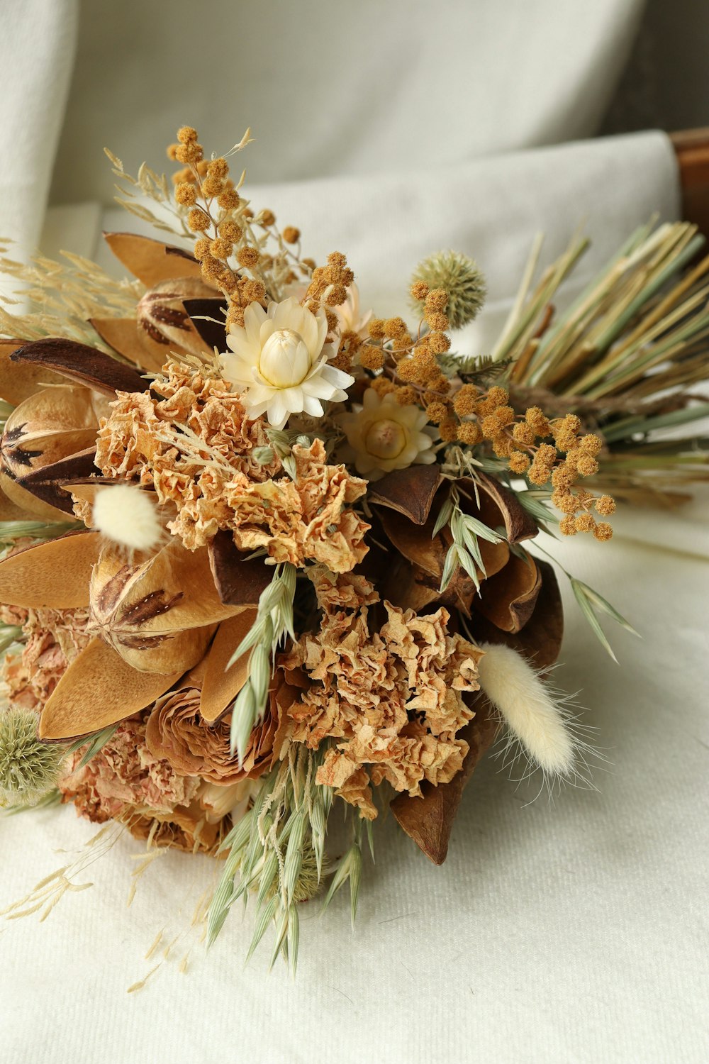 a bouquet of dried flowers on a white cloth