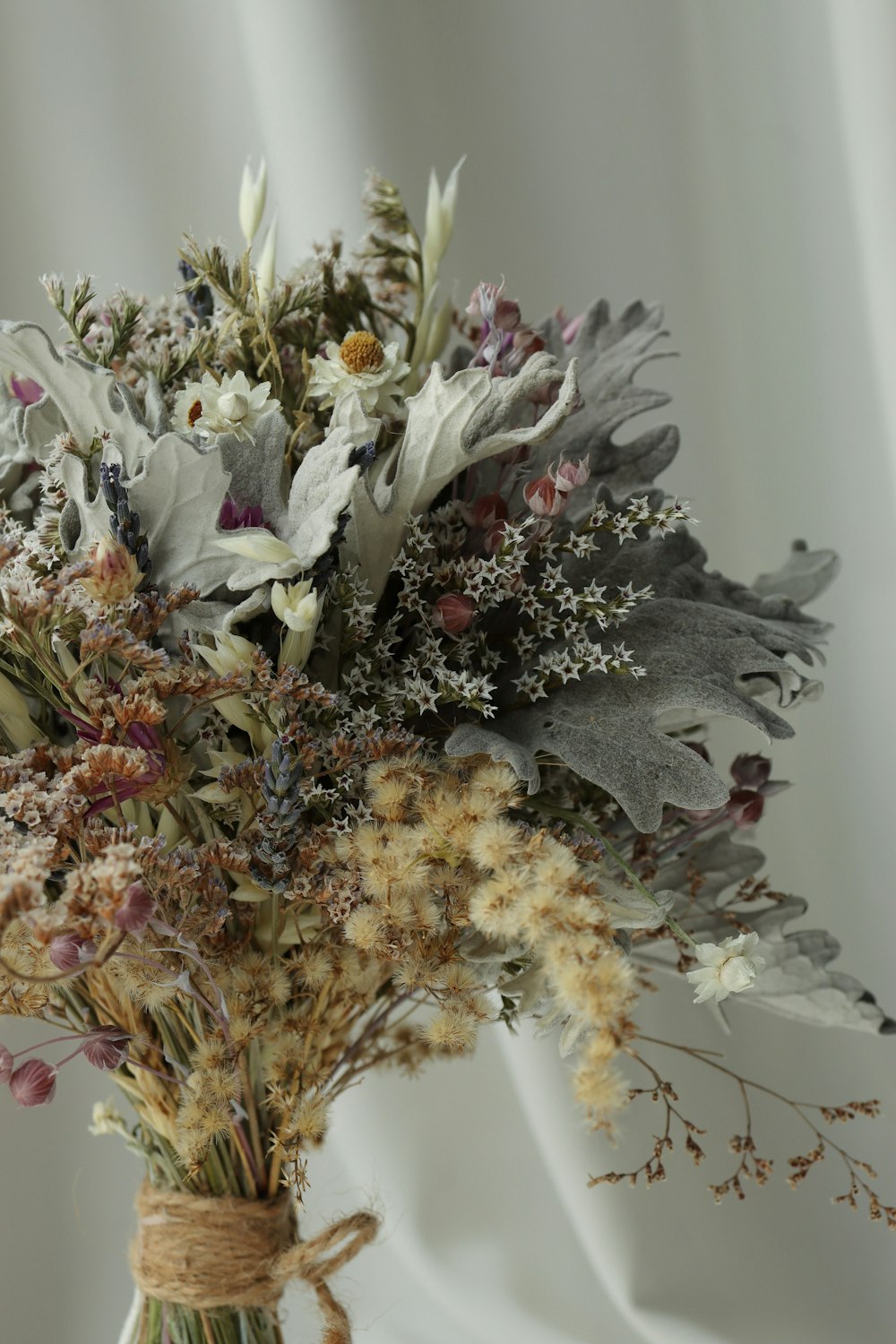 a bouquet of dried flowers in a glass vase