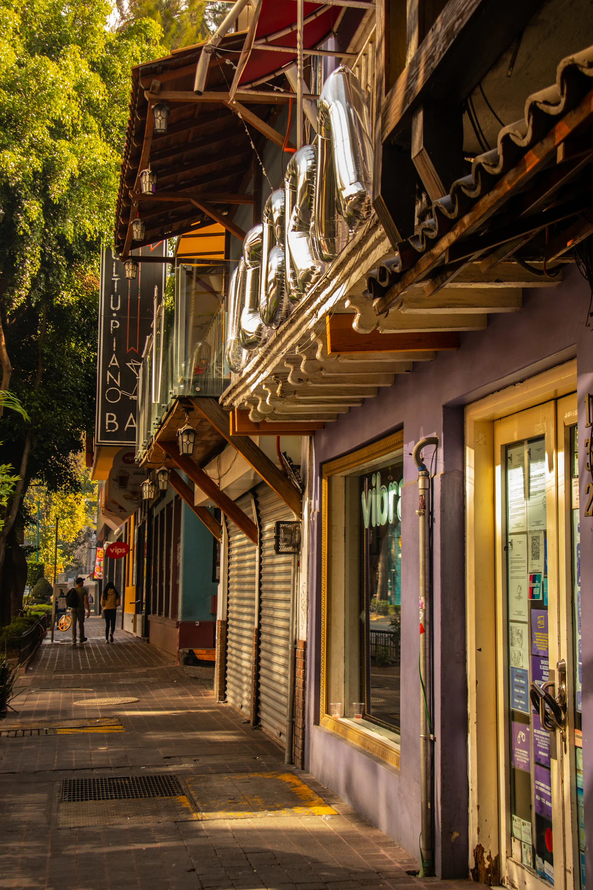 A narrow Mexico City sidewalk lined with shops