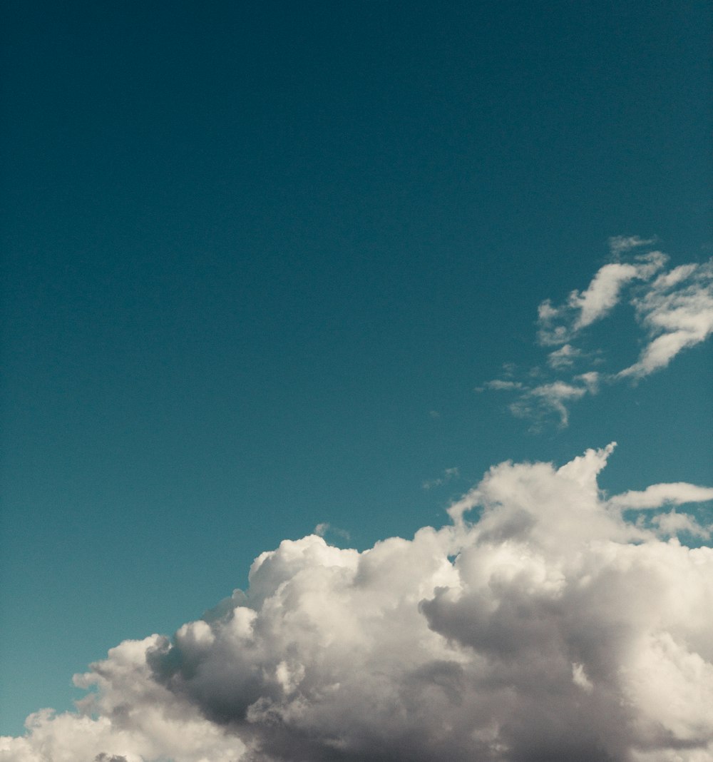 a plane flying through a blue cloudy sky