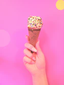 Close-up of a pastel pink ice cream cone with sprinkles on a sunny day